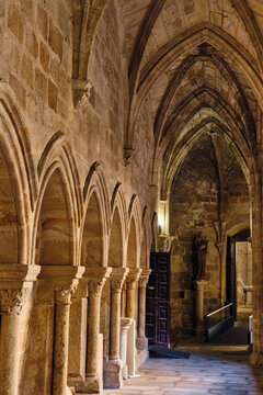 Plasencia, Spain - 03 December 2025: View of the Gothic cloister of the Catedral Nueva de Plasencia featuring stone arches, vaulted ceilings, and a religious statue.