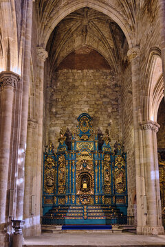 Plasencia, Spain - 03 December 2025: View of the ornate blue and gold altarpiece inside the Catedral Nueva de Plasencia with stone walls and vaulted ceiling.