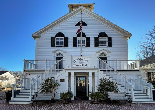 Edgartown, United States - 14 May 2026: View of Edgartown Town Hall, a historic white clapboard building with symmetrical staircases, black shutters, and an American flag.