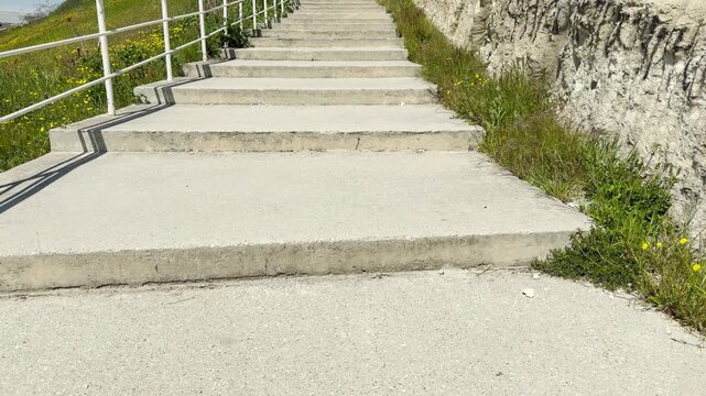 A long path of flat stone stairs climbs toward the horizon under a sunny sky. Walking up the bright walkway fills the air with a sense of peaceful adventure and quiet relaxation.