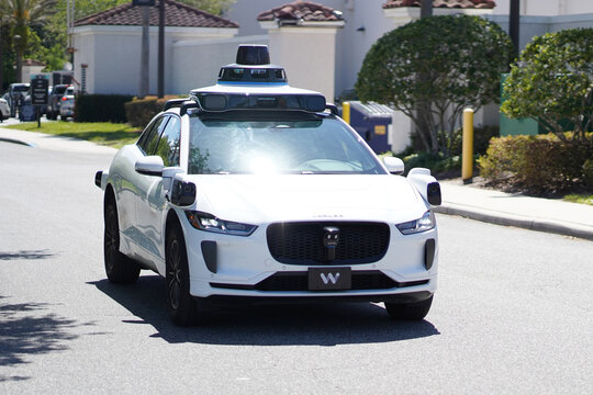 A Waymo autonomous vehicle drives on a sunny street in Florida with rooftop sensors and self driving technology visible in Orlando, Florida on April 11, 2026.