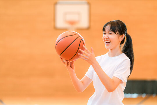体育館でバスケットをする体操着姿の女子中学生・女子高生