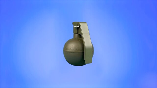 A standard military fragmentation hand grenade rotates slowly in mid-air against a solid blue backdrop. This pre-keyed explosive weapon asset is designed for chroma key compositing in military present