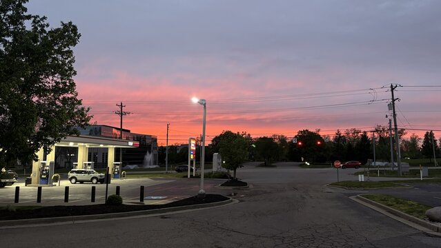 Loveland, United States - 18 April 2026: View of a gas station under a vibrant pink sunset sky with street lights and power lines.