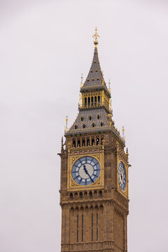 London, United Kingdom - 12 May 2025: View of the iconic Elizabeth Tower and Big Ben clock face with its ornate gothic architecture and golden details against an overcast sky.