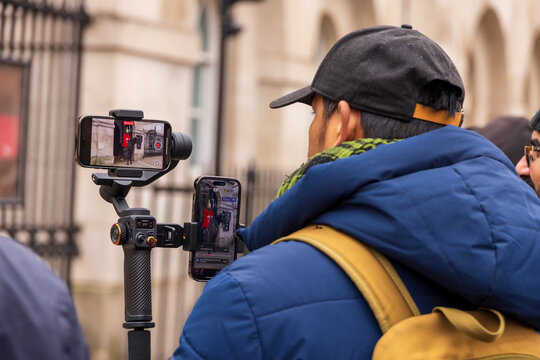 London, United Kingdom - 12 May 2025: View of a tourist using a gimbal and smartphones to film a King's Guard on horseback at Horse Guards Parade.