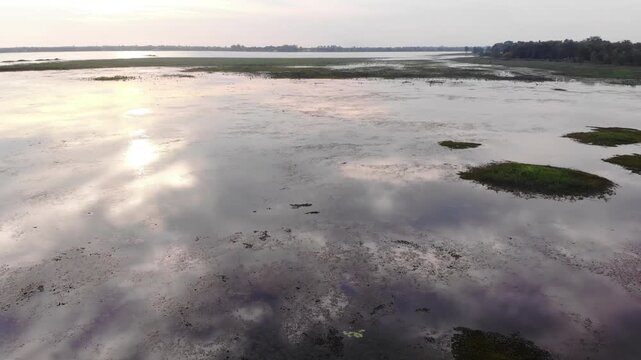 Aerial view of a serene wetland landscape with calm water and grassy areas at sunset.