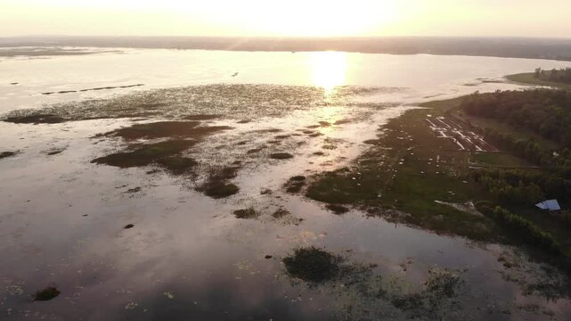 Aerial view of a serene wetland landscape with calm water and grassy areas at sunset.