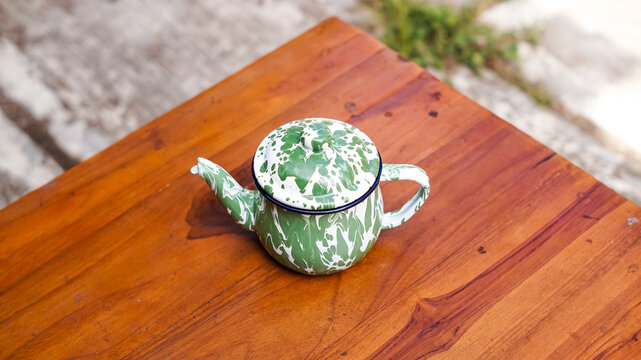 A traditional Indonesian green enamel blirik teapot. Made of iron coated with enamel, it features a distinctive classic green and white striped motif and is often referred to as an old-fashioned teapo