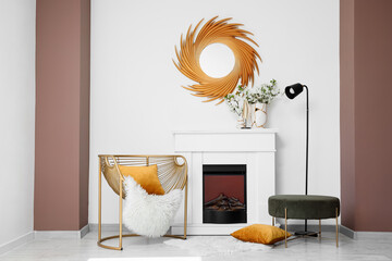 Fototapeta premium Interior of light living room with blooming branches in vases, fireplace and golden armchair