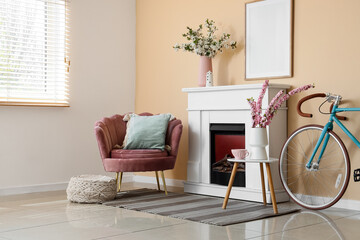 Fototapeta premium Interior of living room with fireplace, bicycle, armchair and blooming branches in vases
