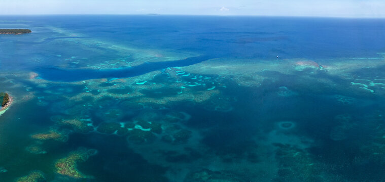 Aerial view of the vibrant coral reef system and turquoise waters surrounding the tropical island of Guanaja, Bay Islands Department, Honduras.