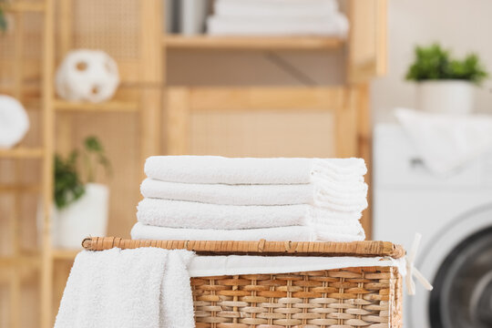 Stack of clean soft towels on laundry basket in bathroom, closeup
