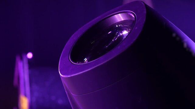 Close-up of a moving stage spotlight fixture changing colors in a dark environment