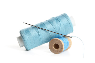Blue sewing thread spools with needle isolated on white background, closeup