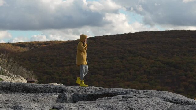 Adventure Hiking Autumn Woman Explores Mountain Summit In Yellow Raincoat. Vertical video.