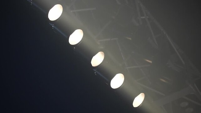 Close-up of moving stage lighting fixtures shifting colors from purple to light