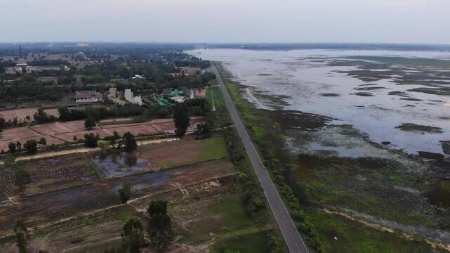 Aerial view of the Huay Saneng reservoir area with green algae on the water surface and lush vegetation in Surin, Thailand.