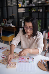 Fototapeta premium Mature asian woman&nbsp;making handmade jewellery accessories handcraft hobby
