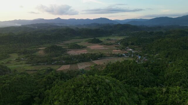 Panoramic aerial drone shot of Virac, Catanduanes with forested hills, open farmland, and broad mountain terrain under soft daylight