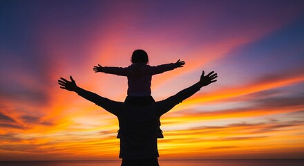 Fototapeta premium Father carrying daughter on shoulders with arms raised against sunset