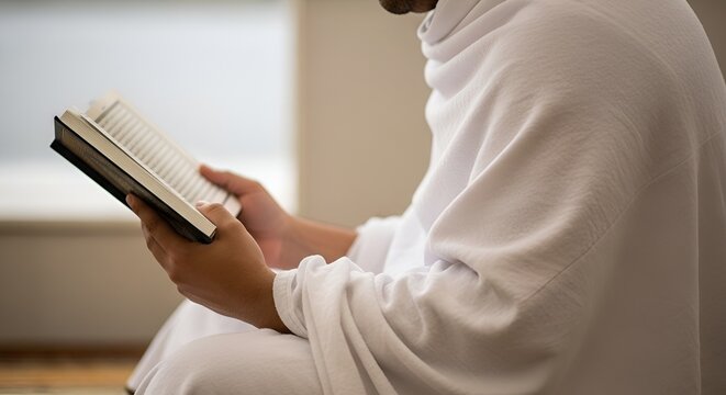Muslim man in ihram reading holy book, pilgrimage, Mecca, Umrah, Quran