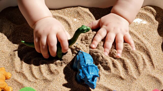Child's Hands Playing with Dinosaur Toys in Sand. Suitable for Montessori Education, Sensory Play Parenting Guides, Early Childhood Activity Video Content