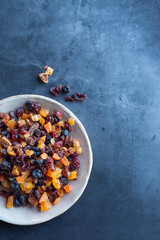 Fototapeta premium Mixed dried fruits in a ceramic bowl on a dark background.