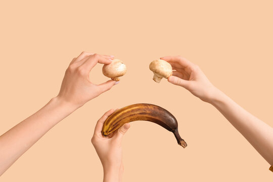 Hands holding fresh mushrooms and overripe banana on beige background, food spoilage and freshness comparison concept