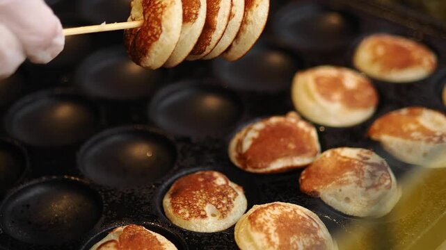Cooking mini pancakes on a hot griddle in a kitchen