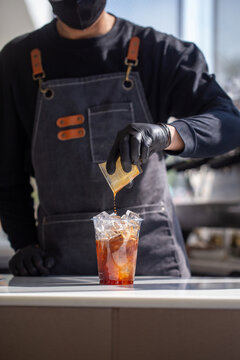 Barista pouring espresso shot over iced milk to make iced latte.