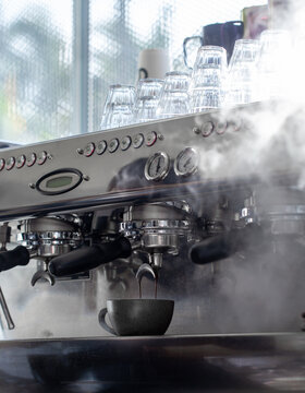 Coffee machine brewing espresso with dramatic steam in modern cafe.