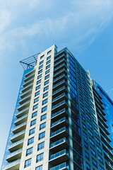 Fototapeta premium Tall building reaches towards the blue sky with many windows and balconies in a city during a sunny day