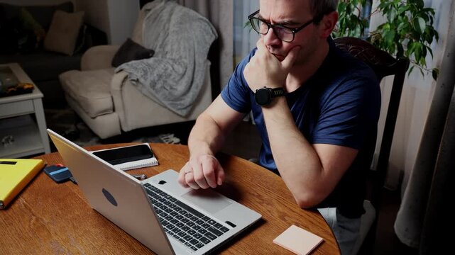 Freelancer focused on work at home desk with laptop and notes in modern workspace setting
