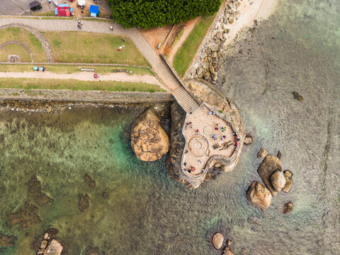 Aerial view of the historic Galle Fort bastion with people on the stone platform overlooking the turquoise ocean and rocky coastline in Galle, Southern Province, Sri Lanka.