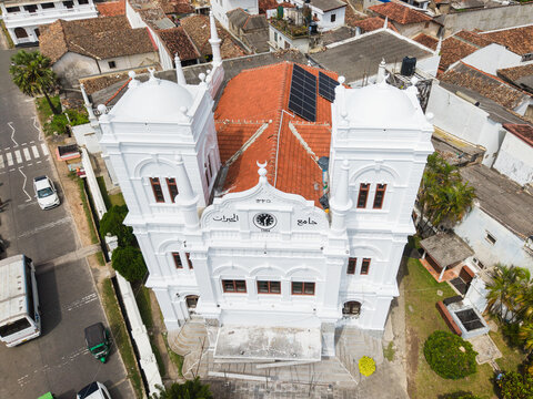 Aerial view of the white Meeran Jumma Mosque featuring two towers and solar panels on a red tiled roof in the historic fort area Galle, Southern Province, Sri Lanka.