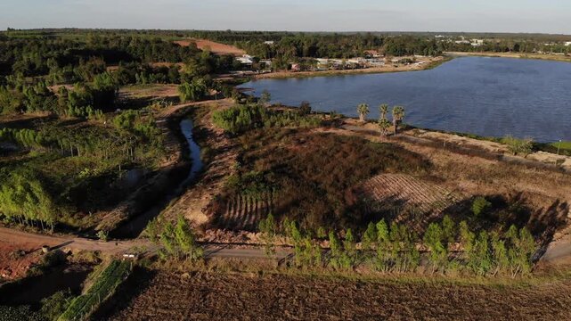 Aerial view of houses and lush vegetation surrounding a small rural town in northeastern of Thailand.

