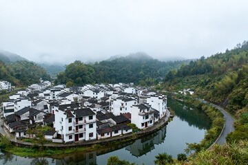 Obraz premium Traditional village by river in misty mountains