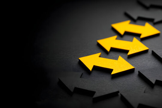 Leadership concept, yellow leader arrow leading black arrows, on black background with empty copy space on left side.