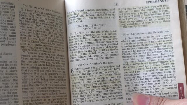 Holy Bible open up to the book of Galatians of the new testament, zooming into Chapter 5 verse 22 on the fruit of the Spirit. New Revised Standard Version.