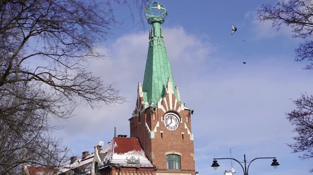 Historic building with tower and clock in cityscape with birds.