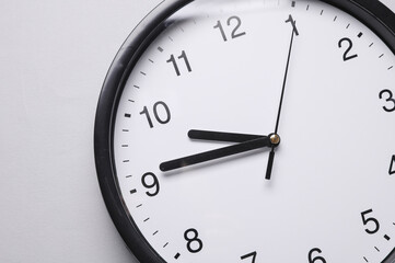 Fototapeta premium Round wall clock with black hands on a gray background. Time concept.