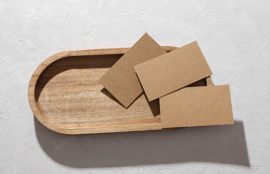 Craft blank business cards mockups with dry grass in a tray on a white concrete background