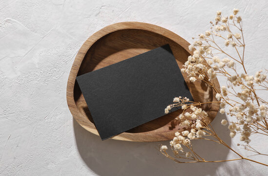 Black blank business card mockup with dry grass in tray on white concrete background