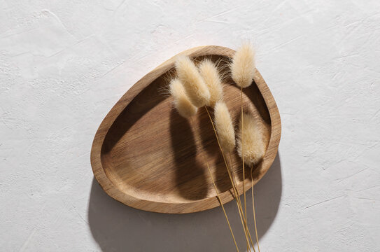 Premium wooden tray with dry grass on white concrete background