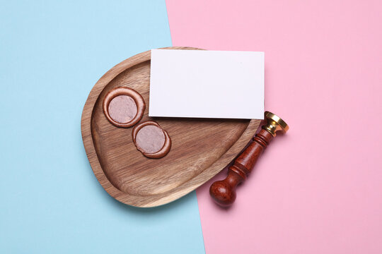 Vintage wax stamp with blank business card in wooden tray on pink blue background. Top view