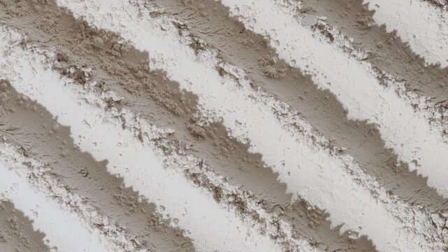 Top view shot of white powder furrows surface illuminated by rotating light casting shifting shadows | Concept of silica powder cosmetic ingredient