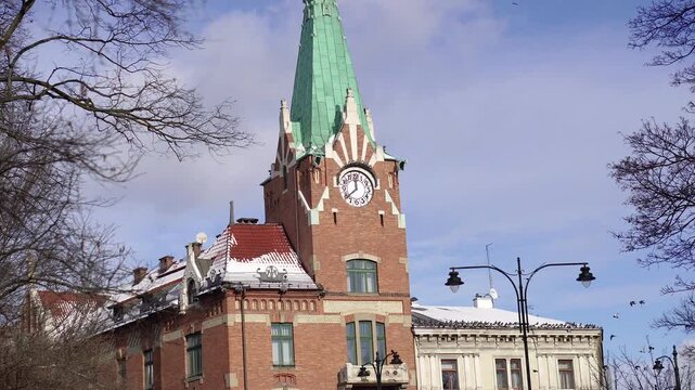 Historic building with tower and clock in cityscape with birds.