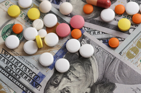 Many different pills on hundred dollar bills. Medicine financing concept