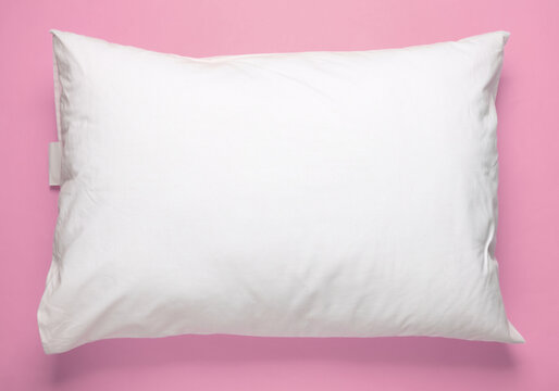White pillow on pink background. Top view